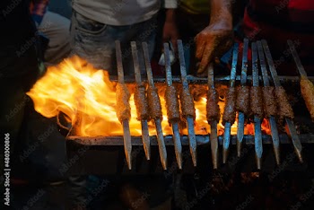 Spicy chicken seekh kababs are being grilled with heat in barbeque with metal skewers,at evening for sale as street food in Old Delhi market. It is famous for spicy Indian non vegetarian street foods.
