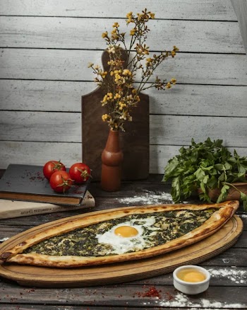Spinach pide with egg on wood serving board