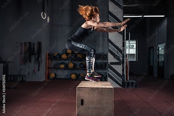 Sporty girl jumping over some boxes in a cross-training gym