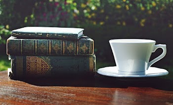 Stack Of Books Beside A White Cup And Saucer