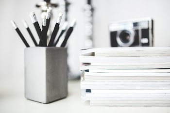 Stack of magazines &amp; pencils in gray cup