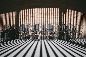 Stacked chairs along the wall covered by shadows of the building