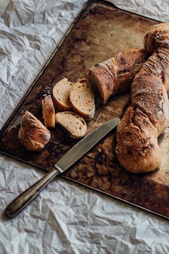 Stainless Steel Bread With Slices of Bread on Chopping Board