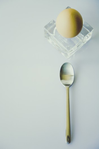 Stainless Steel Spoon Beside Yellow Egg on Clear Glass Fragment