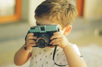 standing boy using camera during daytime