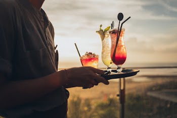Standing Man Wearing Gray Shirt Holding Tray With Drinks during Golden Hour