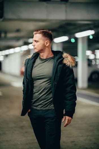 standing man wearing jacket and black pants