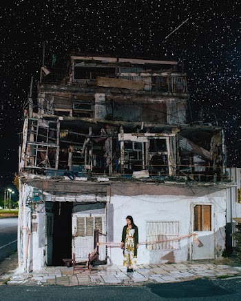 Standing Woman in Front of White and Gray Concrete House