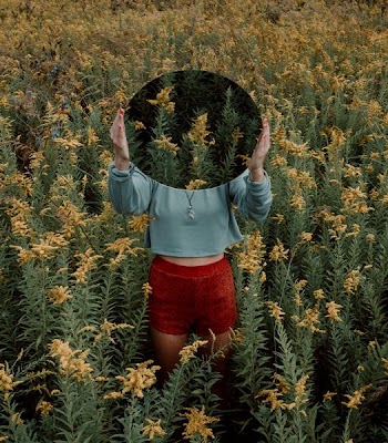 standing woman surrounded by yellow flower field during daytime