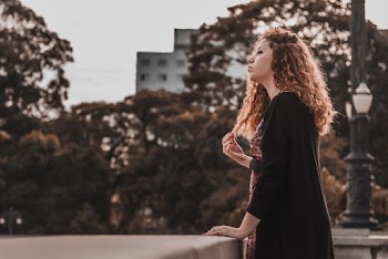 Standing Woman Touching Her Hair and Concrete Handrail during Day