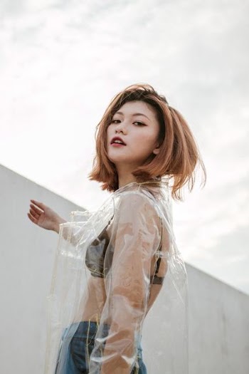 standing woman wearing clear plastic raincoat under white sky during daytime