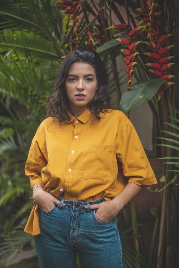 Standing Woman With Hands on Pockets Beside Heliconia Rostata Plants