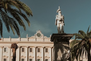 Statue In Front Of A White Concrete Building