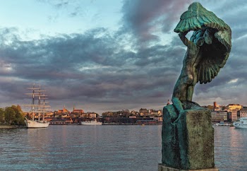 Statue Near Body of Water Under Cloudy Sky