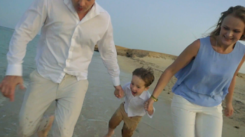 Steadicam slow motion of a young family running along the sea and ...