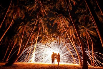 steel wool photo of couple holding hands under palm trees