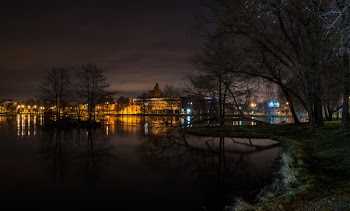 Still Body of Water Next to Lighted Beige Buildings during Nighttime