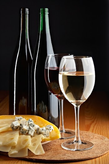 still life with cheese, red and white wines on the black background