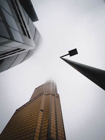 street light near city buildings under gray sky during daytime