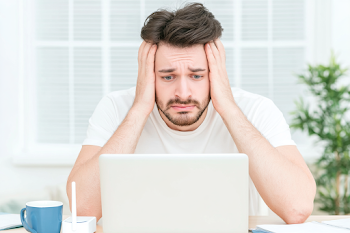 Stressed Young Adult Man at Home Office Desk