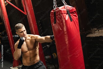 Strong young mma fighter and red punching bag