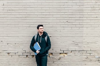Student Leaning Against Brick Wall