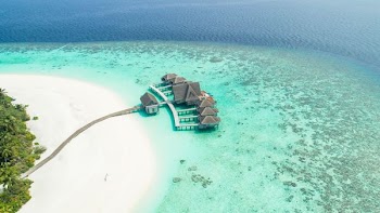 Stunning resort on a pristine island in the Maldives surrounded by coral reefs and ocean