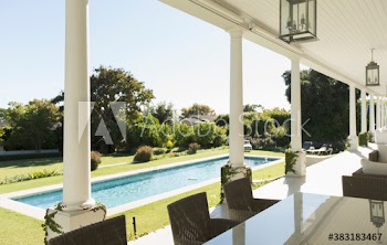 Sunny lap pool outside luxury home patio