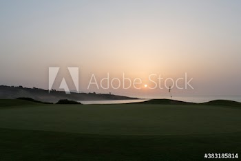 Sunset behind tranquil ocean golf course