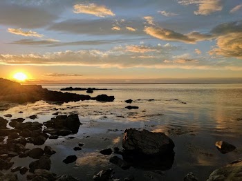 Sunset Over Water By Rocky Shore