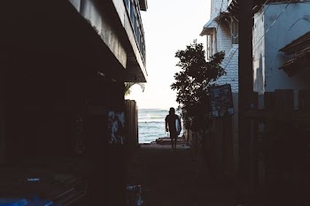Surfer walking through the alley towards the ocean