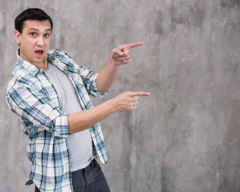 Surprised young guy with opened mouth pointing away Free Photo