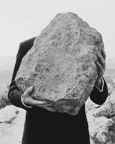 Surreal Burden: Man in Suit Carrying a Stone Surreal Burden: Man in Suit Carrying a Stone
