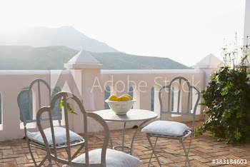 Table and chairs on sunny idyllic mountain balcony