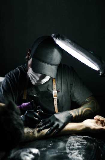 Tattoo artist in black gloves drawing a tattoo on a person's arm