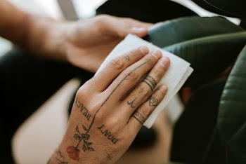 Tattooed hand cleaning the houseplant leaf | Free stock photo | High Resolution image