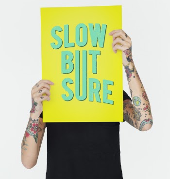 Tattooed Person Holding Slow but Sure Signage