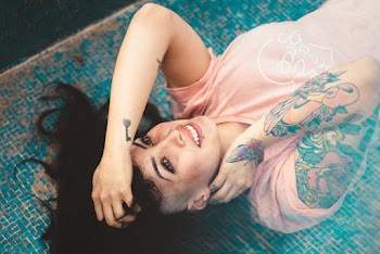 Tattooed Woman Wearing Pink Crew-neck Shirt Lying on Blue Ceramic Tiles