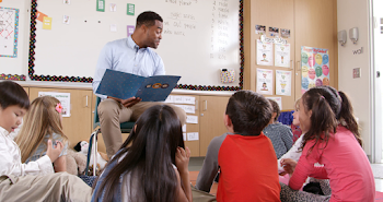 Teacher reading kids a story in an elementary school class Stock ...