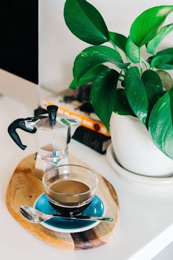 teacup filled with coffee beside moka pot