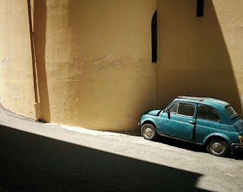teal 3-door hatchback parked beside beige concrete building