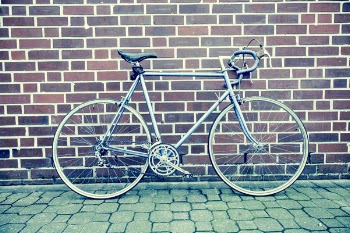 Teal and Black Road Bike Near Black and Brown Brick Wall