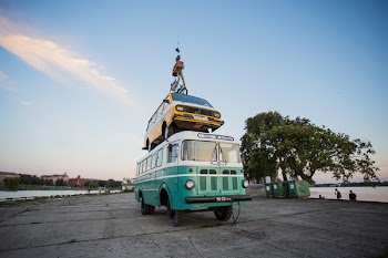 Teal Bus With Yellow Car on Roof