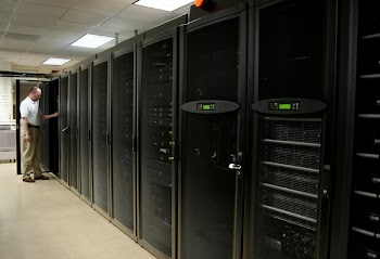 Technician working on racks of 1u and 2u servers in a computer room.