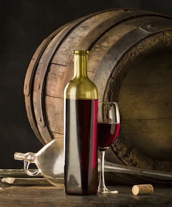 The bottle of red wine and glass and wine-cask