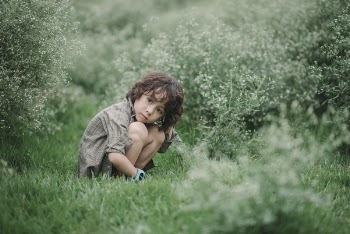 The boy is sitting in the flower field