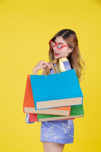 The girl holds a fashion shopping bag and holds a smart card on a yellow background. Free Photo