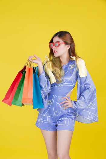 The girl holds a fashion shopping bag and holds a smart card on a yellow background. Free Photo