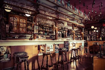 The interior of a bar with stools, glass cups and empty bottles attached to the roof in Madrid