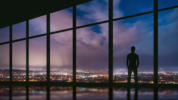 The man stand at the panoramic window on the background of night ...